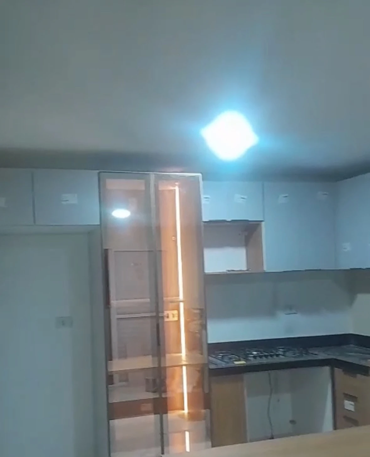 Foto da cozinha com cristaleira de vidro iluminada por LED e bancada em L